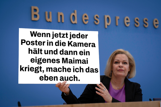 Bundesinnenministerin Faeser hält in der Bundespressekonferenz ein Plakat hoch mit der Aufschrift „Wenn jetzt jeder Poster in die Kamera  hält und dann ein eigenes Maimai kriegt, mache ich das eben auch.“
